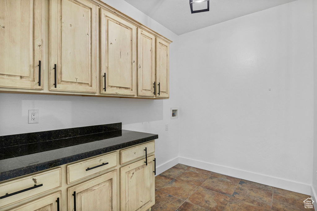 Clothes washing area with baseboards, cabinet space, washer hookup, and stone finish floor