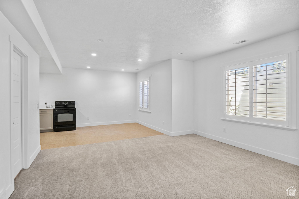 Unfurnished living room with light colored carpet, recessed lighting, baseboards, and a wealth of natural light