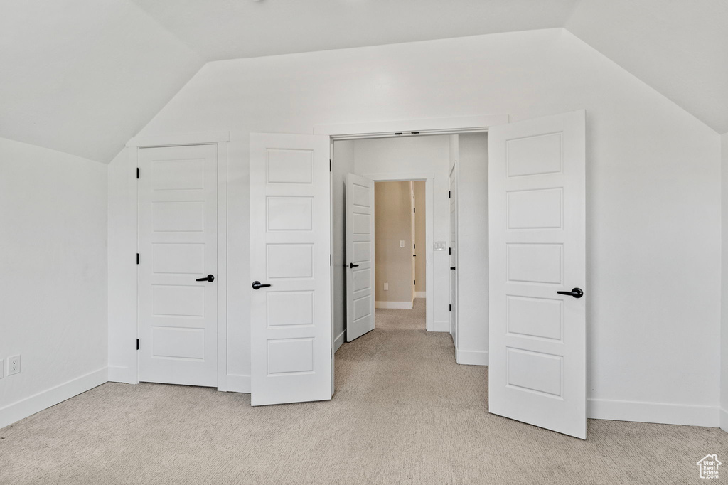 Additional living space featuring baseboards, vaulted ceiling, and light carpet