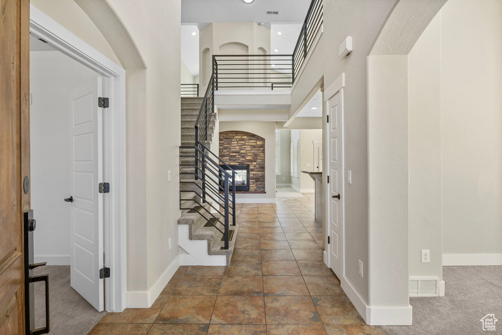 Entrance foyer with baseboards, a high ceiling, visible vents, and stairway