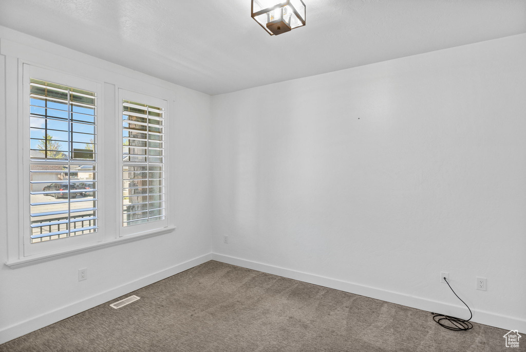 Carpeted empty room featuring baseboards and visible vents