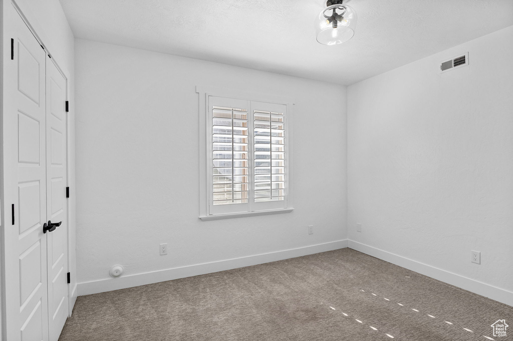 Empty room with baseboards, visible vents, and carpet