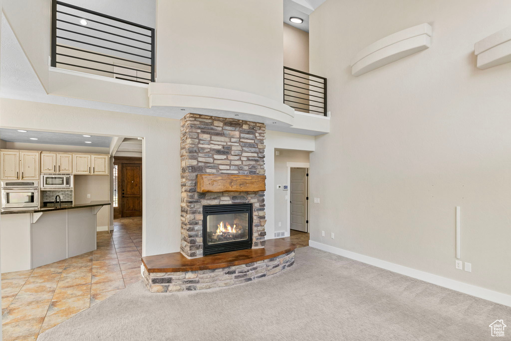 Unfurnished living room featuring a high ceiling, a sink, a fireplace, recessed lighting, and baseboards