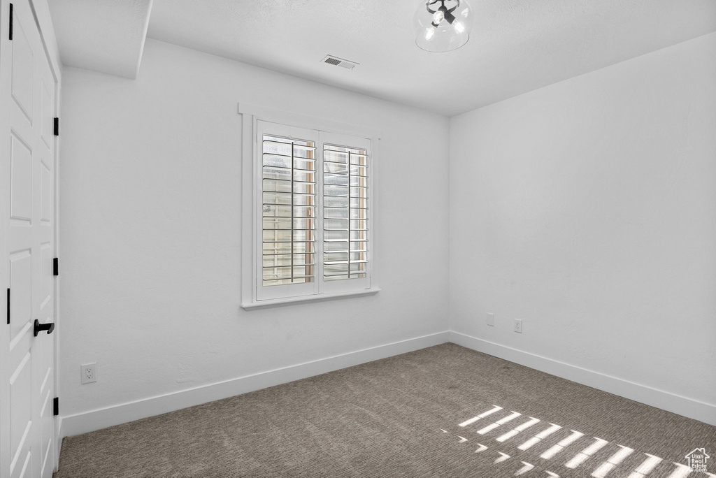 Empty room featuring carpet floors, baseboards, and visible vents