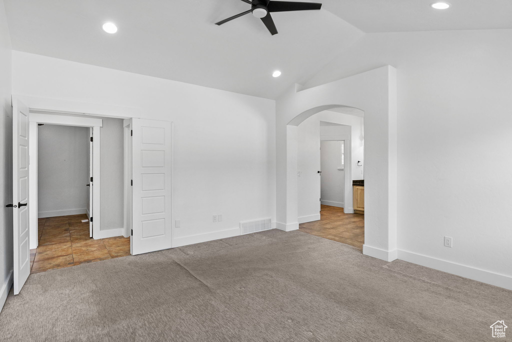Unfurnished bedroom featuring carpet floors, baseboards, recessed lighting, arched walkways, and vaulted ceiling