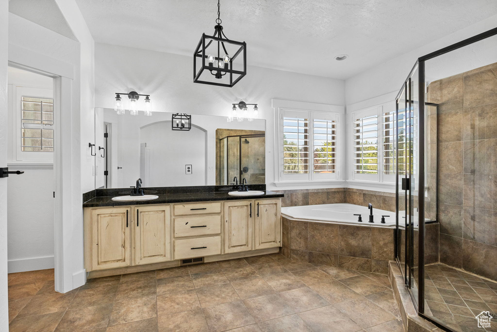 Bathroom featuring a garden tub, a sink, a stall shower, and double vanity