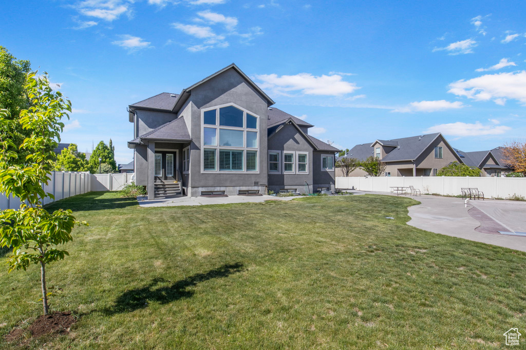 Back of property featuring a fenced backyard, stucco siding, a yard, and a patio area