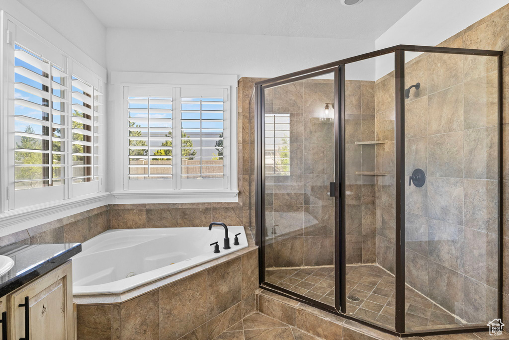 Bathroom featuring a garden tub, vanity, a healthy amount of sunlight, and a shower stall