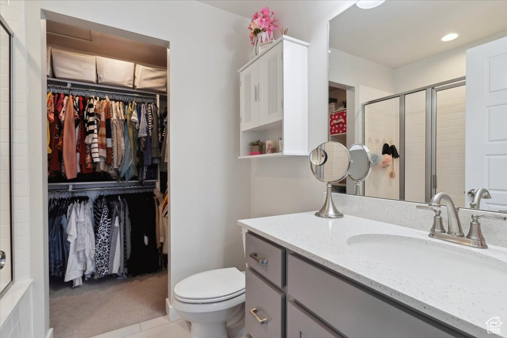 Full bathroom with toilet, a tile shower, a walk in closet, and vanity