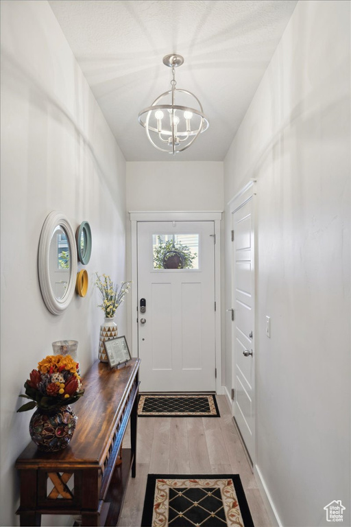 Doorway to outside with light wood-style flooring and a chandelier