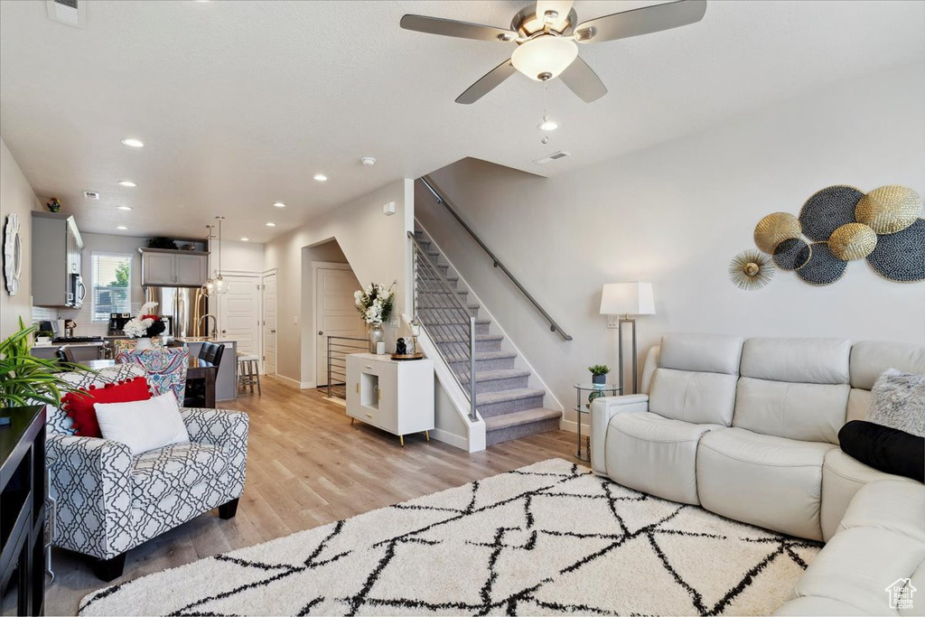 Living room with baseboards, light wood-style floors, stairway, recessed lighting, and a ceiling fan