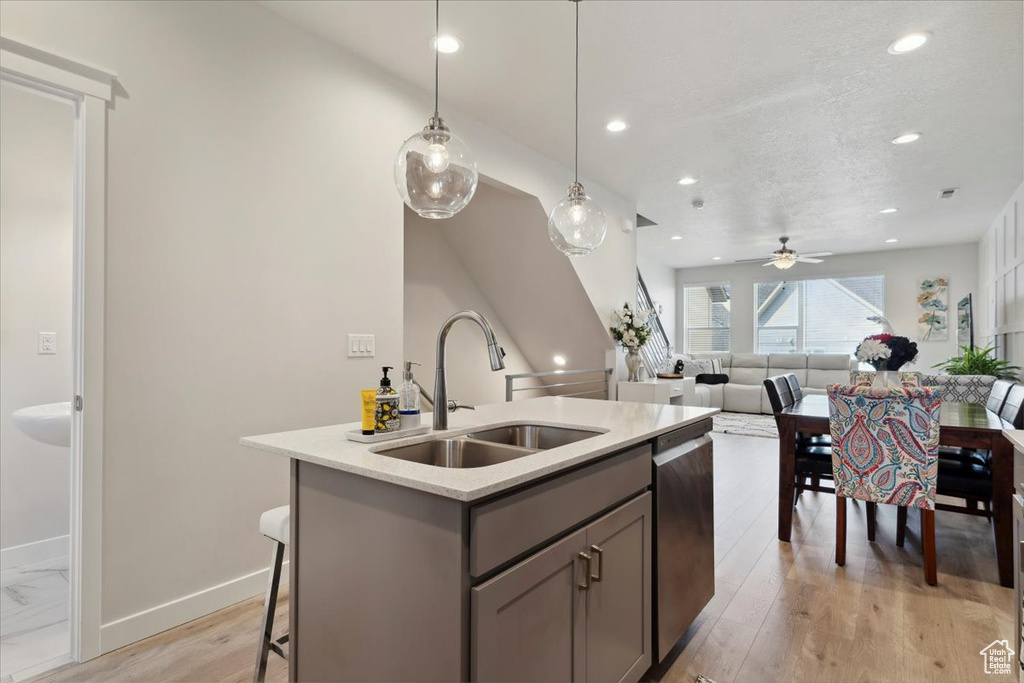 Kitchen featuring a sink, a kitchen island with sink, recessed lighting, stainless steel dishwasher, and gray cabinetry
