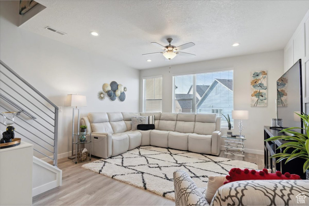 Living area featuring stairway, baseboards, light wood-style floors, and visible vents
