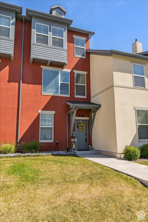 Townhome / multi-family property featuring stucco siding and a front yard