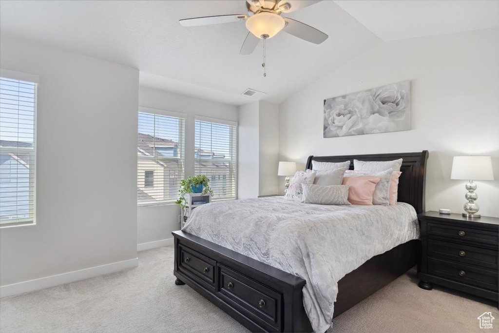 Bedroom featuring ceiling fan, light colored carpet, baseboards, lofted ceiling, and visible vents