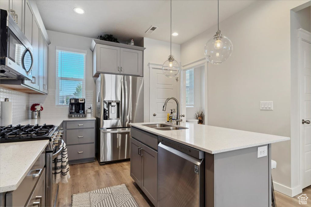 Kitchen with visible vents, appliances with stainless steel finishes, a sink, gray cabinetry, and light wood-style floors