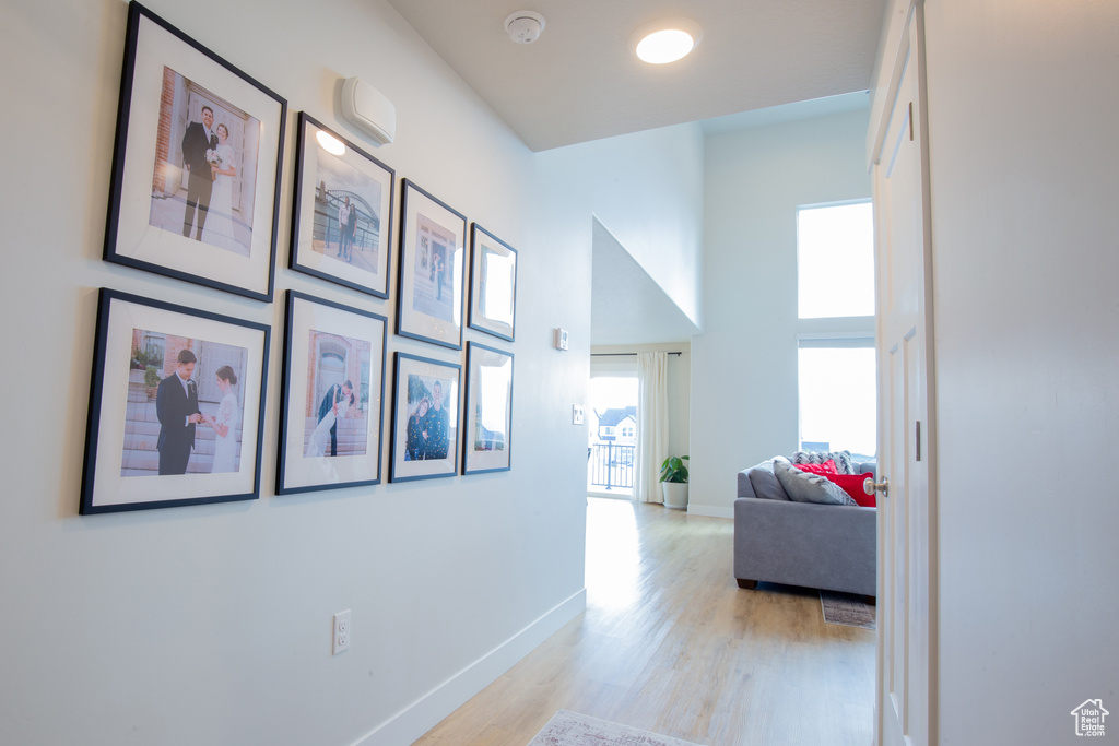 Hall featuring baseboards, a high ceiling, and light wood finished floors