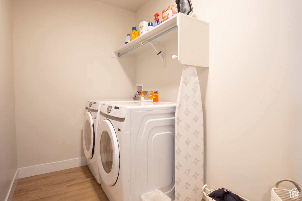 Clothes washing area with baseboards, laundry area, light wood-style flooring, and washer and dryer