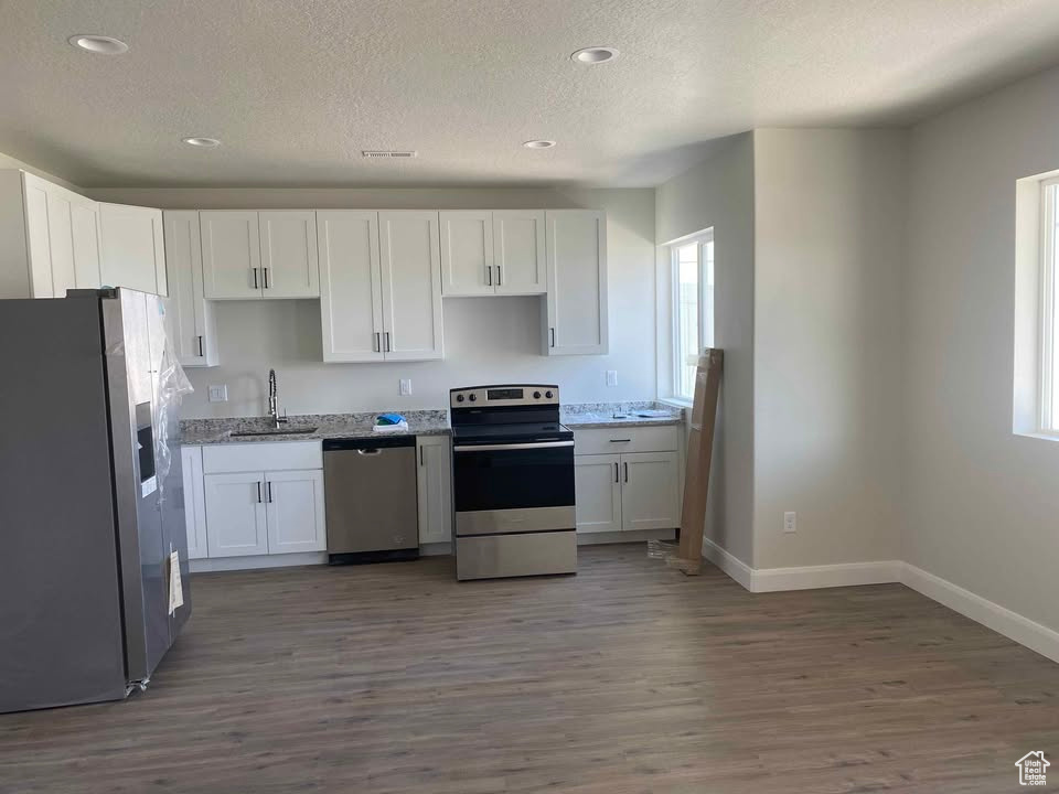 Kitchen featuring stainless steel appliances, baseboards, a sink, and a textured ceiling