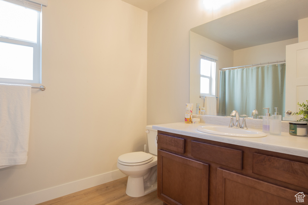 Bathroom with vanity, toilet, baseboards, wood finished floors, and a shower with curtain