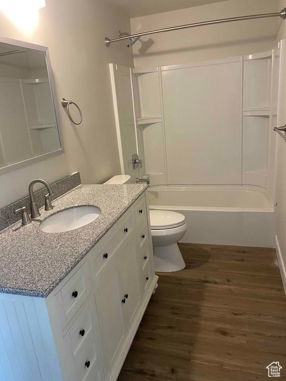 Full bath with vanity, washtub / shower combination, toilet, and wood finished floors