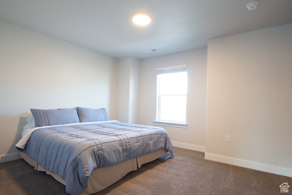 Carpeted bedroom with baseboards and visible vents