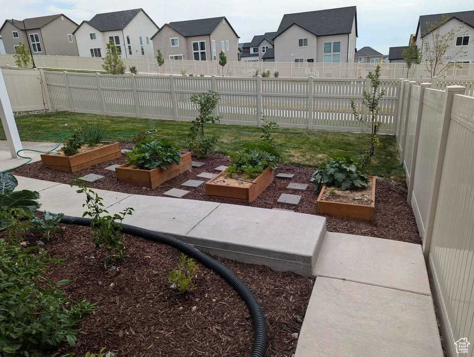 View of yard featuring fence, a residential view, and a vegetable garden