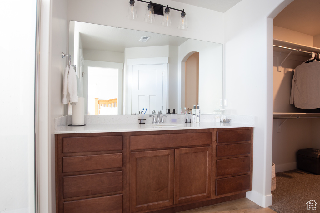 Bathroom with a spacious closet, visible vents, and vanity
