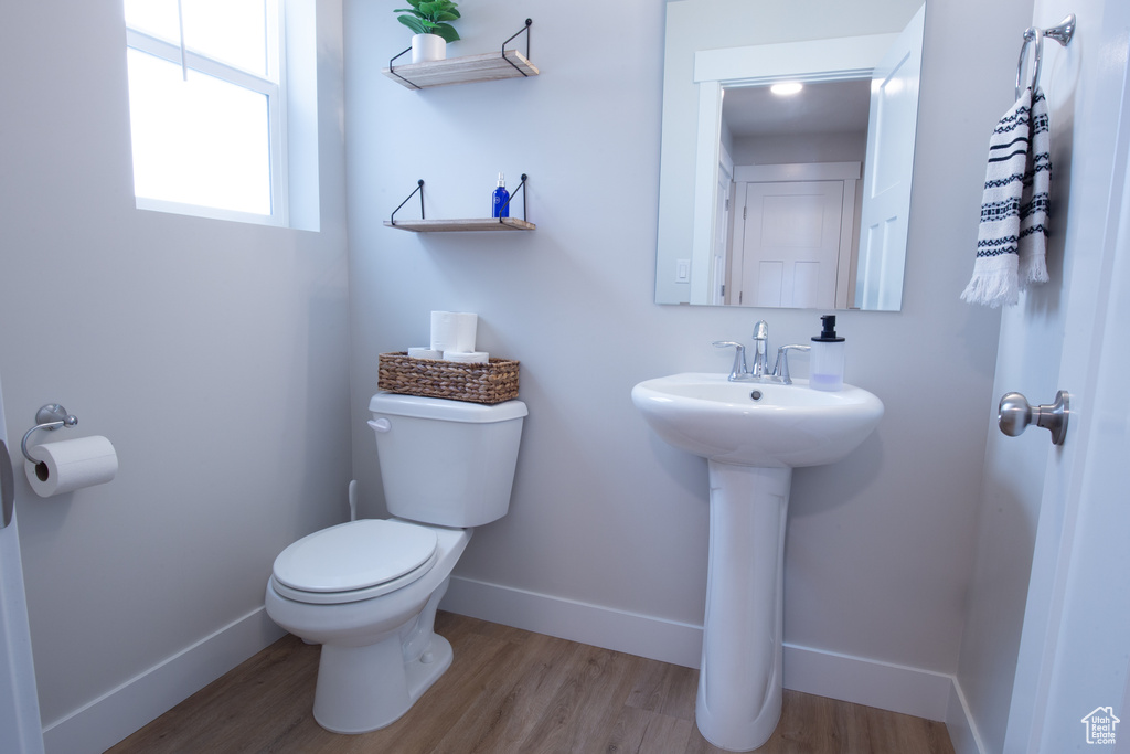 Bathroom with toilet, baseboards, a sink, and wood finished floors
