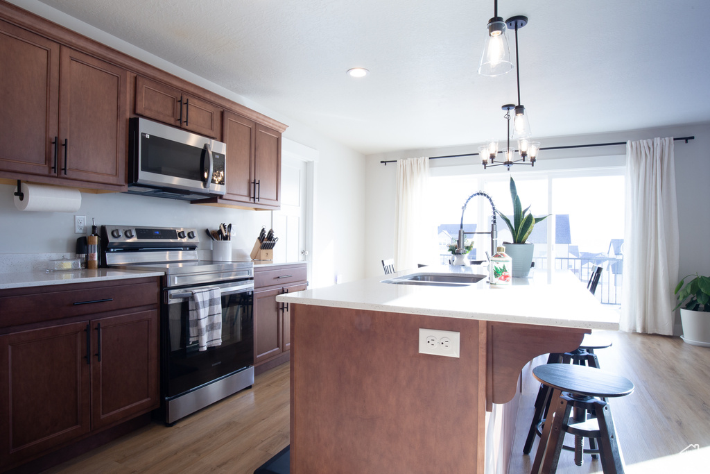 Kitchen with a sink, light wood finished floors, a breakfast bar area, and stainless steel appliances