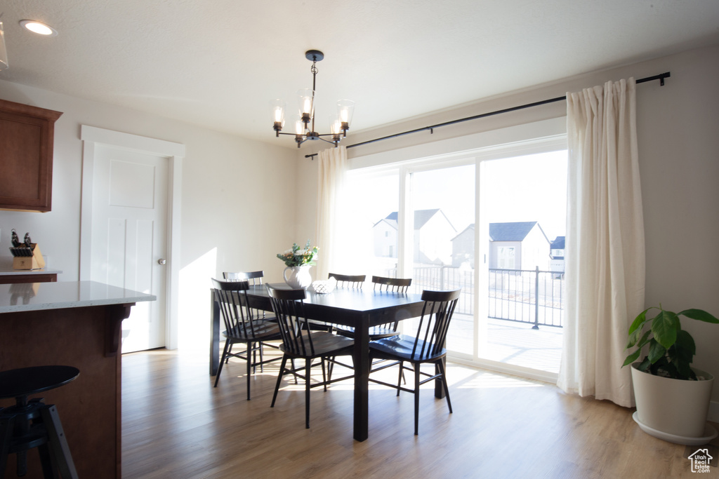 Dining room with light wood-type flooring, recessed lighting, and a notable chandelier