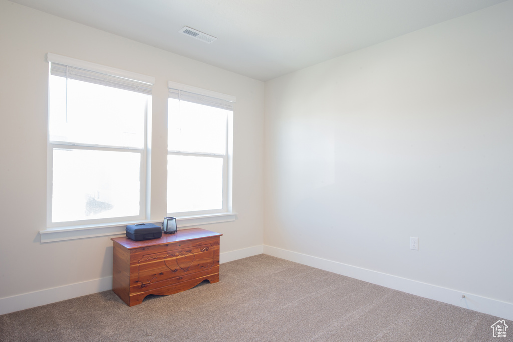 Carpeted spare room featuring baseboards, visible vents, and plenty of natural light