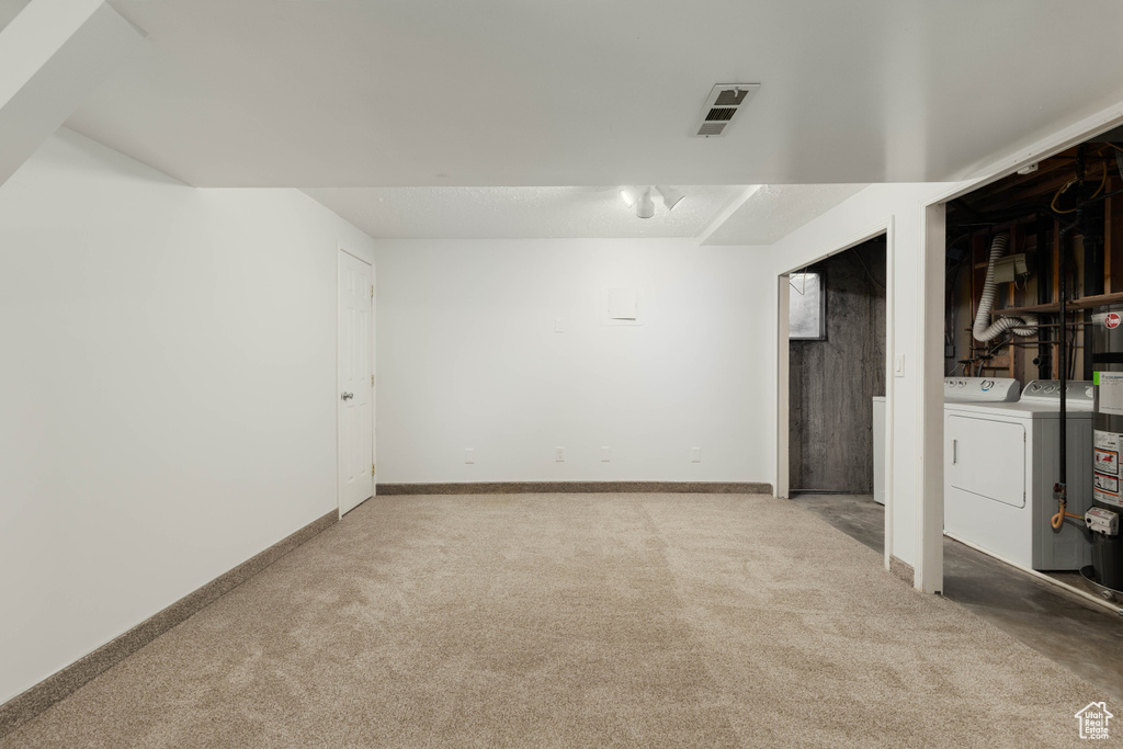 Finished basement with visible vents, washer and clothes dryer, carpet, and baseboards