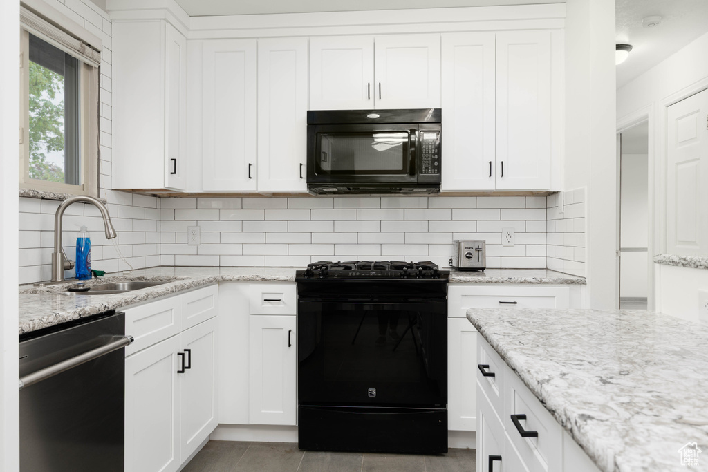 Kitchen with a sink, decorative backsplash, white cabinets, and black appliances