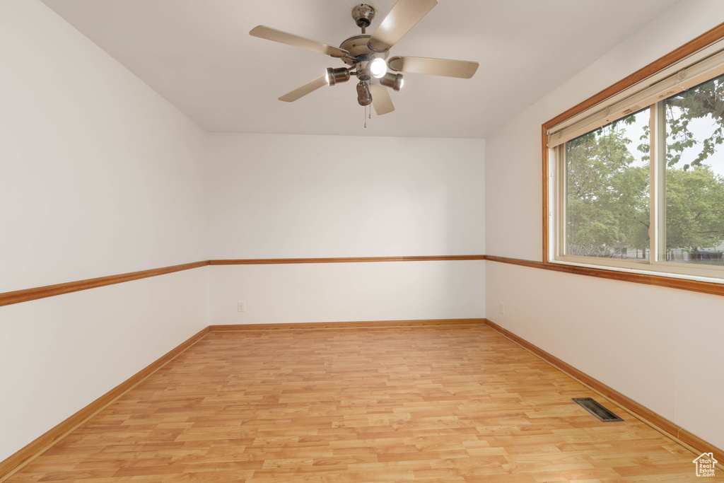 Spare room with a ceiling fan, baseboards, visible vents, and light wood finished floors