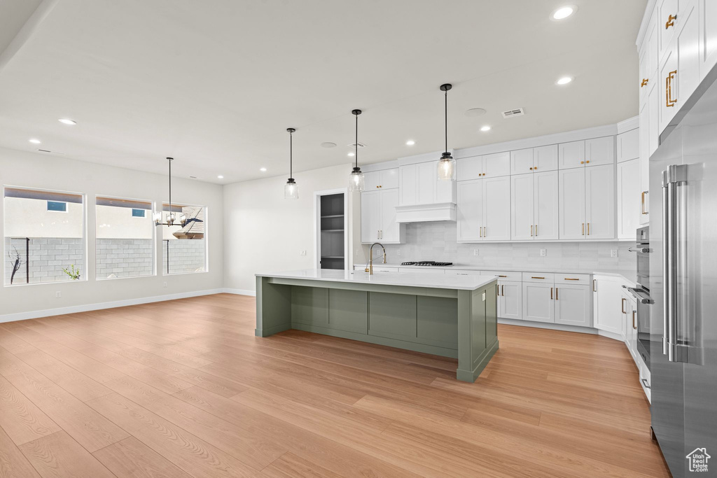 Kitchen featuring decorative backsplash, recessed lighting, light countertops, white cabinets, and light wood-style flooring