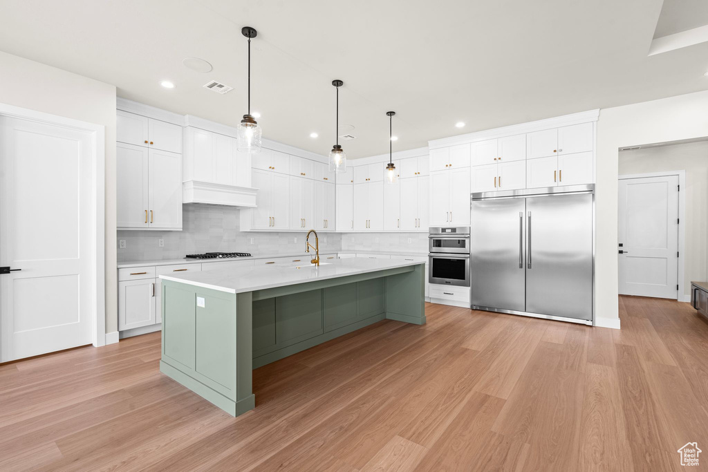 Kitchen featuring light countertops, stainless steel appliances, white cabinetry, and light wood-type flooring