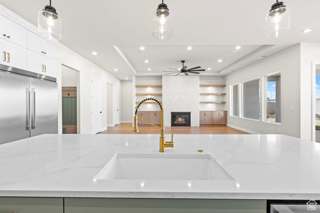 Kitchen featuring a sink, a raised ceiling, a ceiling fan, and open floor plan