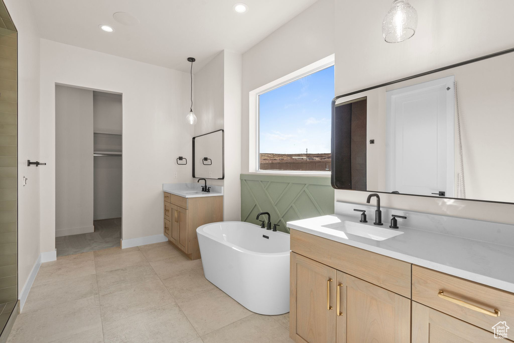 Full bath with recessed lighting, a freestanding bath, two vanities, and a sink