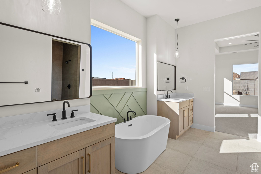 Full bath featuring a freestanding tub, tiled shower, two vanities, and a sink
