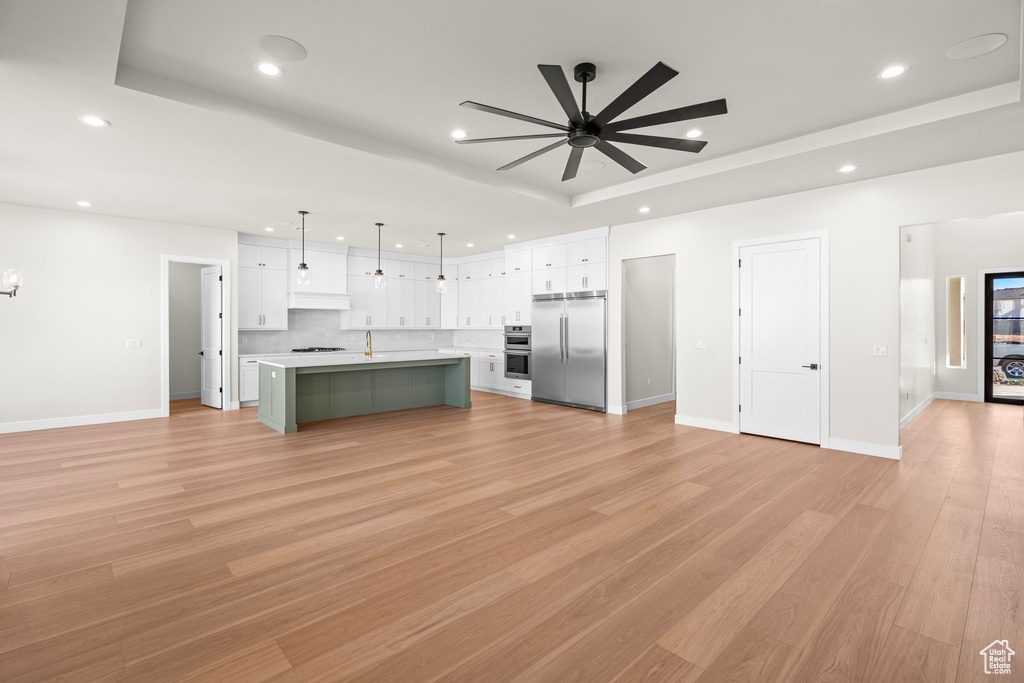 Kitchen with appliances with stainless steel finishes, light countertops, a ceiling fan, white cabinetry, and a tray ceiling