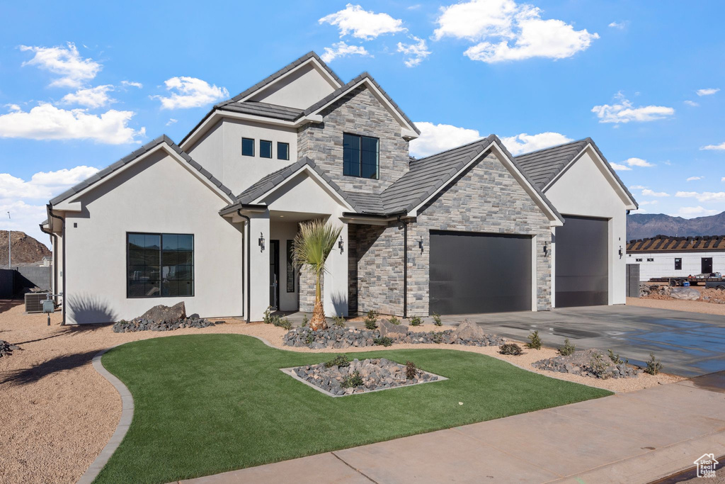 View of front facade with stucco siding, driveway, a front lawn, and stone siding