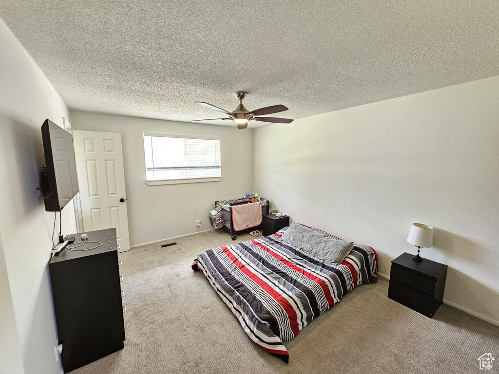 Bedroom with carpet floors, a textured ceiling, and ceiling fan