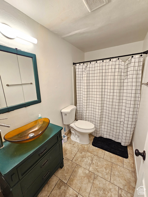 Bathroom with a shower with curtain, visible vents, vanity, tile patterned floors, and toilet