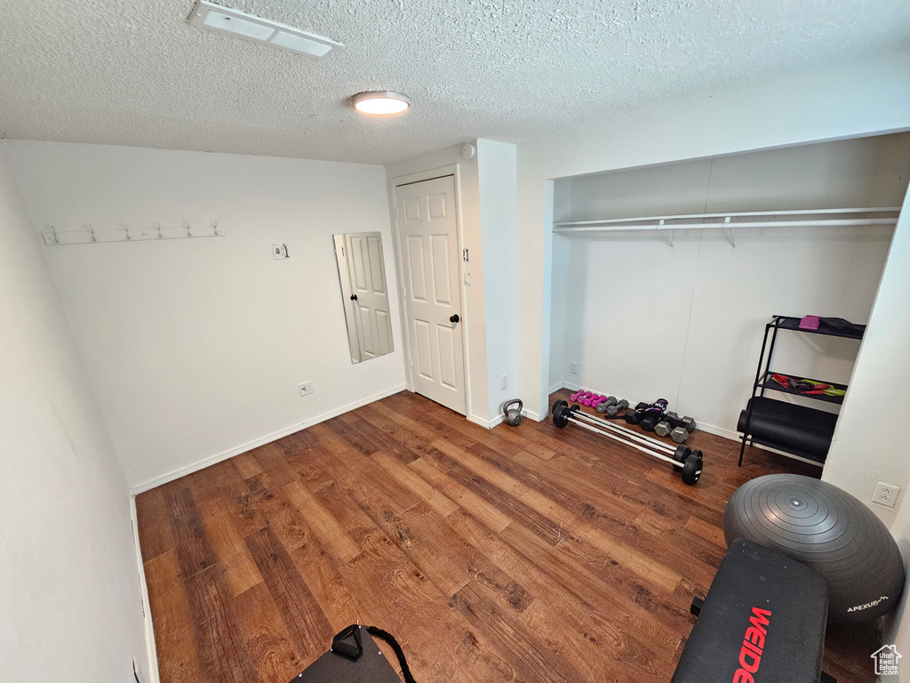 Exercise area with baseboards, a textured ceiling, and wood finished floors