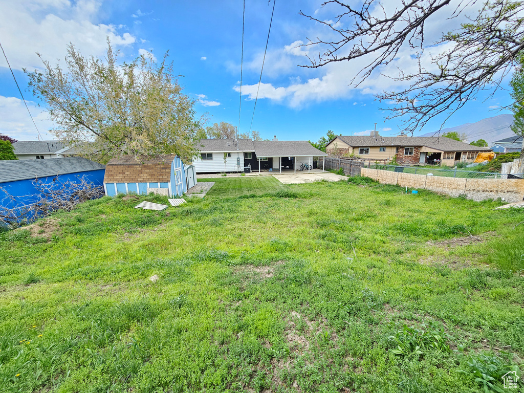 View of yard featuring a fenced backyard, a patio, an outbuilding, and a shed