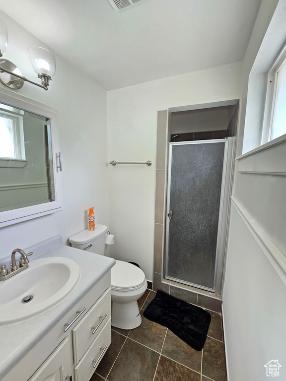 Full bathroom featuring vanity, toilet, tile patterned floors, a healthy amount of sunlight, and a stall shower
