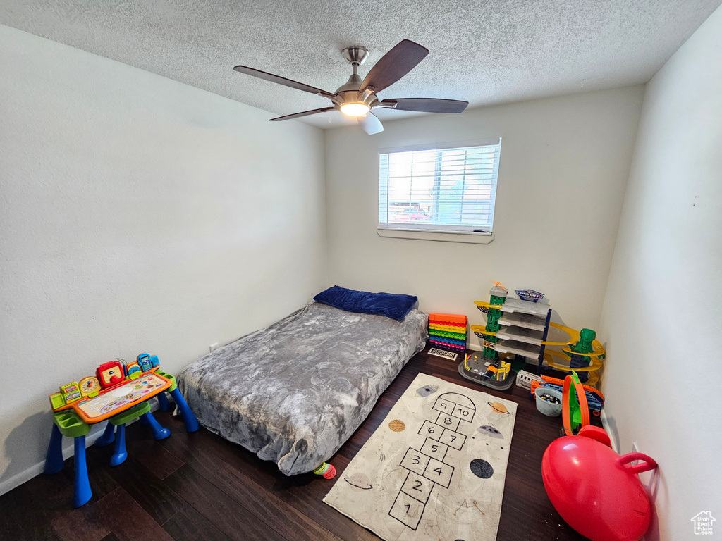Bedroom with a ceiling fan, a textured ceiling, and wood finished floors