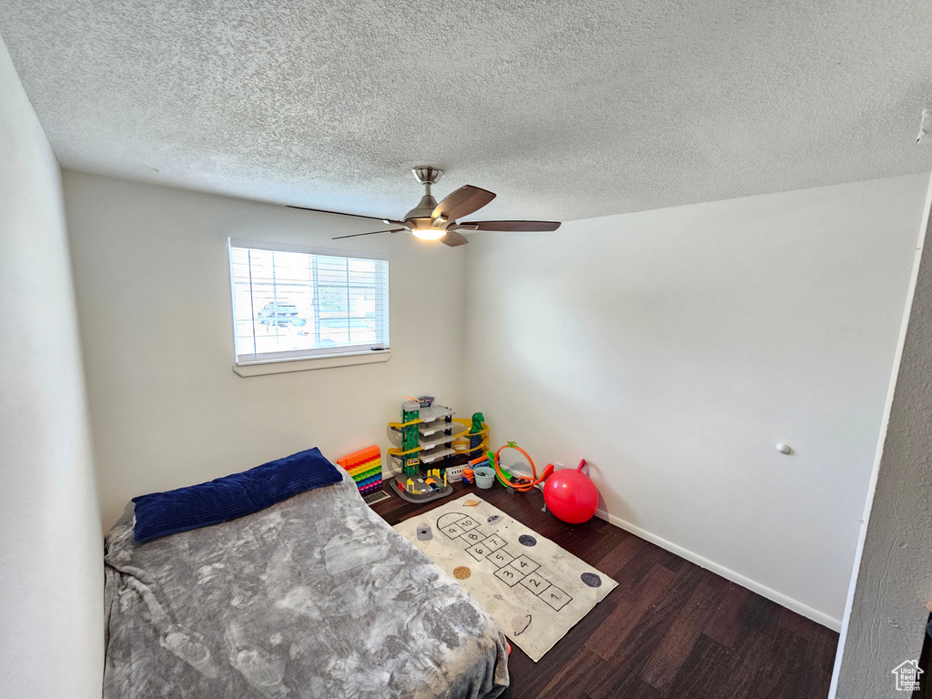 Bedroom featuring baseboards, a textured ceiling, ceiling fan, and wood finished floors