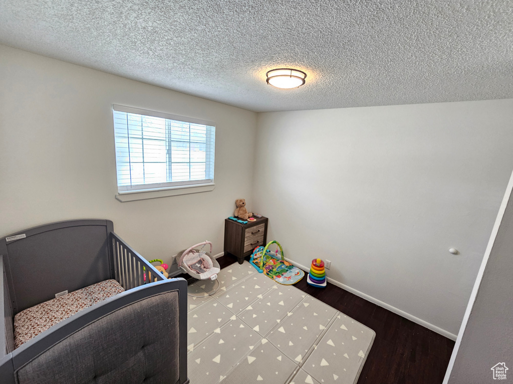 Unfurnished bedroom featuring baseboards, a textured ceiling, and wood finished floors
